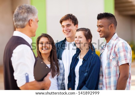 middle aged high school teacher talking to students during break