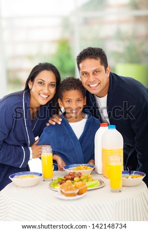 cute indian family standing together behind breakfast table
