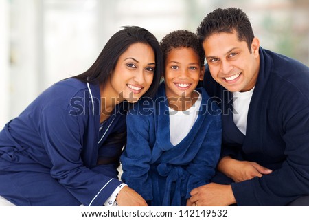 cute young indian family in their nightclothes sitting on bed