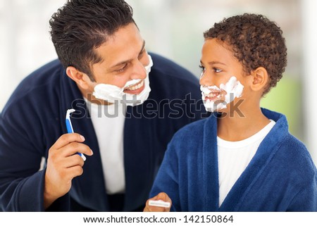 playful father and son shaving together at home bathroom
