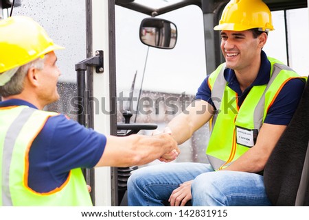 two warehouse forklift drivers handshaking when shift change over