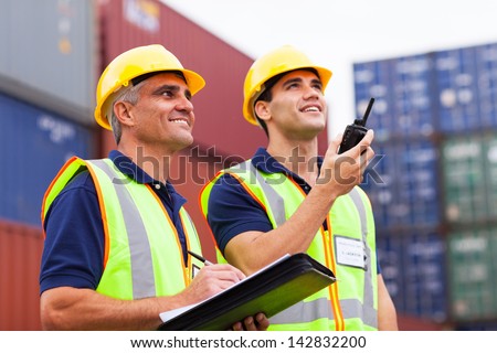 two harbor workers monitoring containers loading