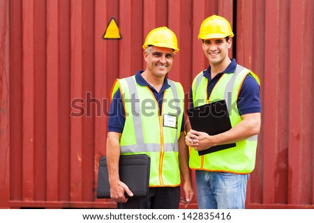 two shipping company workers standing in front of containers