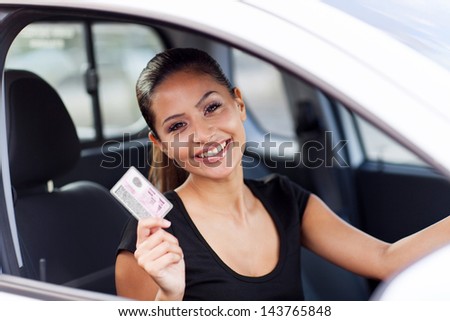 cheerful young woman showing a driving license she just got