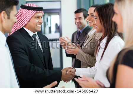 cheerful group of business team welcoming arabian businessman