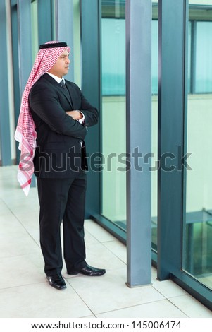 thoughtful arabian businessman inside an office building looking outside the window