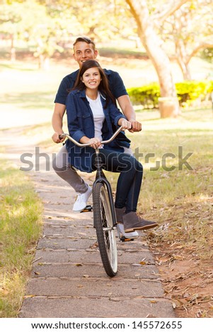 cheerful teen couple riding a bike outdoors
