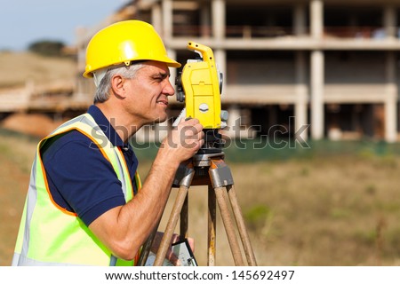 Senior land surveyor working with theodolite at construction site