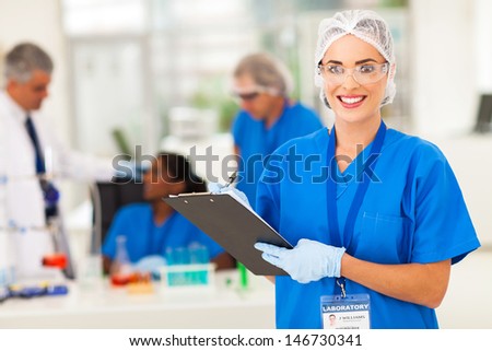 cheerful female medical researcher writing report after doing lab experiments