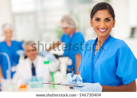 cheerful young indian medical researcher writing report in the lab