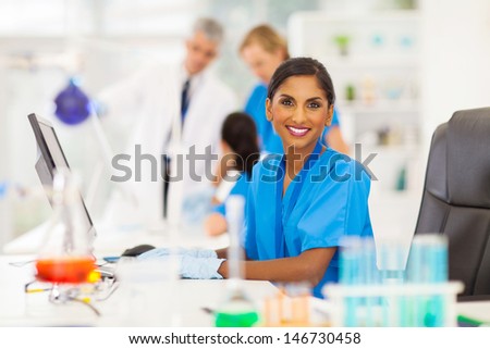 cheerful indian laboratory worker using computer in lab