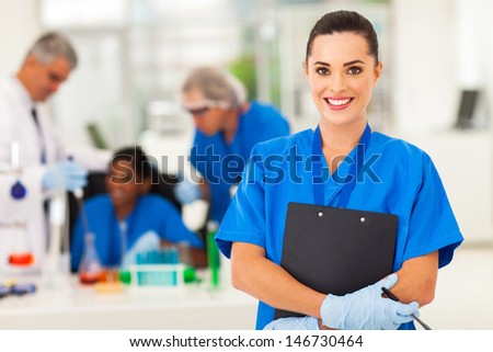 attractive young female lab technician in lab with colleagues
