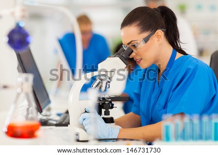 beautiful young scientist using microscope in lab