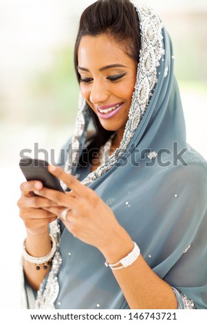 smiling indian woman in traditional clothes reading emails on smart phone