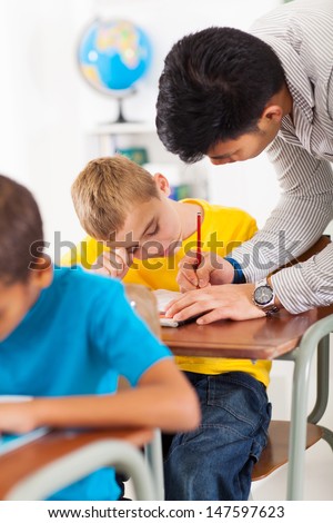 caring teacher helping primary school student in classroom