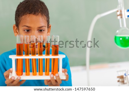 cute male primary school student in science class holding tubes
