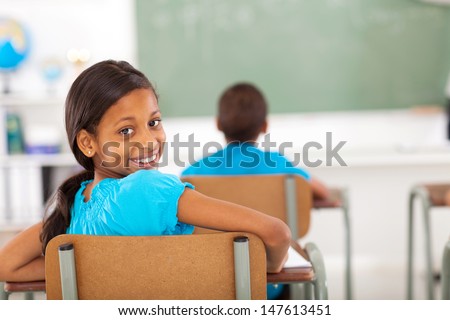 cute primary school girl in classroom looking back