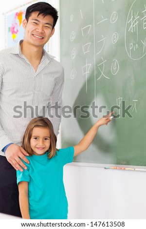 preschool girl with teacher pointing chinese language answer on chalkboard