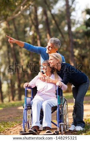 loving mid age couple taking senior mother for a walk outdoors