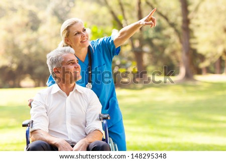 beautiful healthcare worker taking disabled patient for a walk outdoors