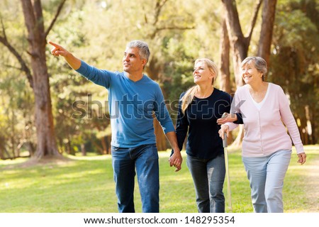 cheerful middle aged couple taking elderly mother for a walk in forest