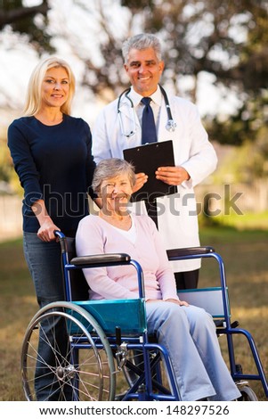 happy disabled senior woman on wheelchair and daughter meeting retirement village doctor outdoors
