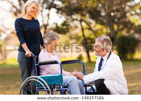 male doctor talking with handicapped senior woman at the retirement home