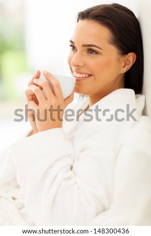 relaxed woman on bed drinking morning coffee and daydreaming