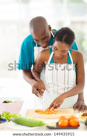 Lovely Afro American Couple Chopping Tomato Together In Kitchen