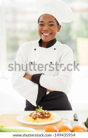pretty female african chef with arms crossed standing in hotel kitchen
