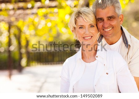 cute mid age couple outdoors looking at the camera