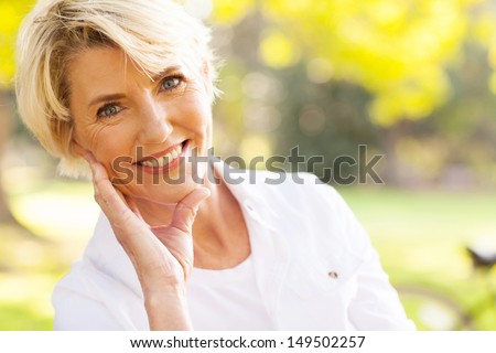 portrait of lovely middle aged woman sitting at the park