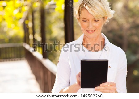 beautiful senior woman using tablet computer outdoors