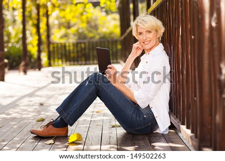 Beautiful Mid Age Woman Using Tablet Computer Outdoors