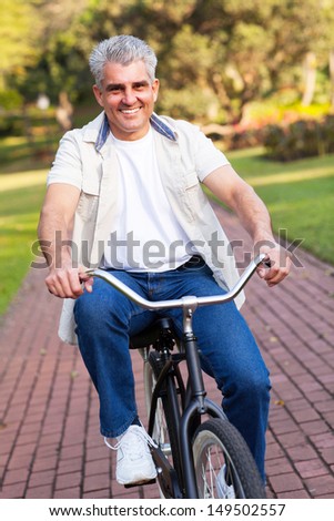 happy middle aged man riding a bike at the park