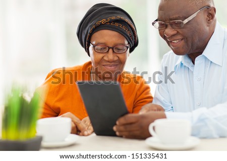 Lovely Elderly African Couple Using Tablet Computer At Home