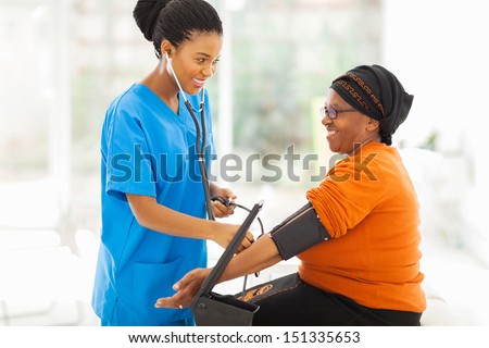 Smiling African Nurse Checking Senior Patient\'S Blood Pressure