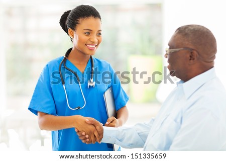 Friendly African American Medical Nurse Handshaking With Senior Patient