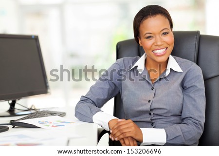 smiling african businesswoman sitting in office looking at the camera