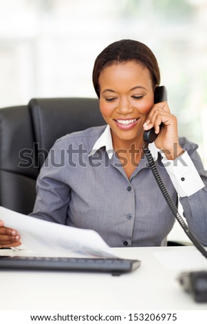 happy african american office worker talking on landline phone
