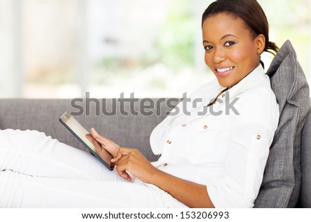 beautiful young african woman using tablet computer at home
