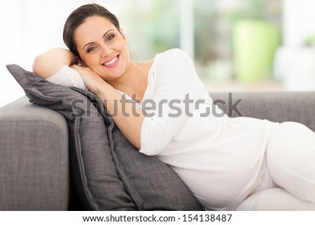 pregnant woman lying on a couch looking happy