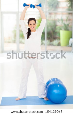 cheerful pregnant woman lifting dumbbells at home