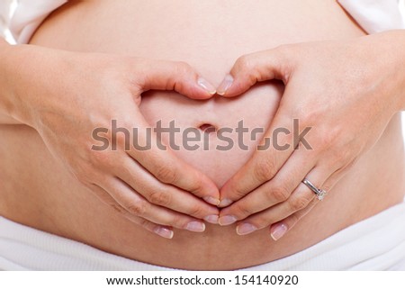 pregnant woman making heart shape with hands over her stomach