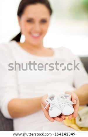 close up portrait of mother to be holding baby shoes