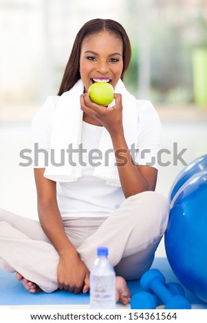 young african american woman eating apple after exercise
