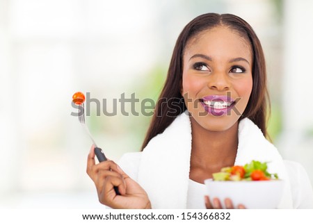 cute black woman eating vegetable salad at home