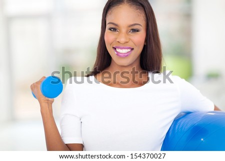 cheerful african woman exercising with dumbbell at home
