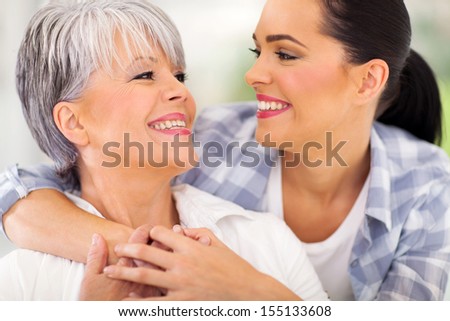 cheerful middle aged mother and young adult daughter looking at each other