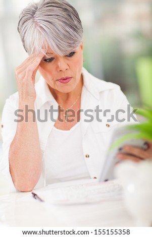 middle aged woman holding a calculator and making payment